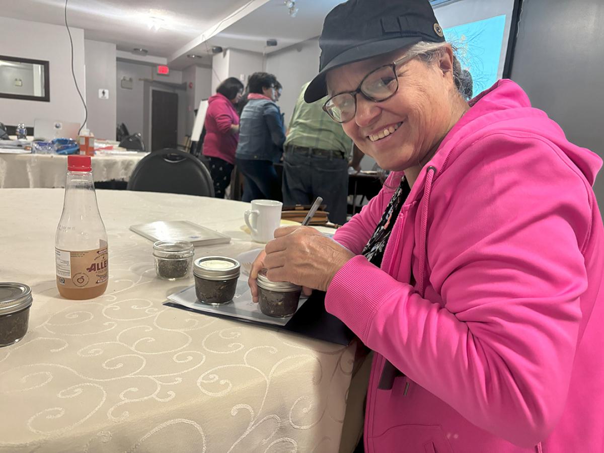 A woman labels a jar with herbs. 